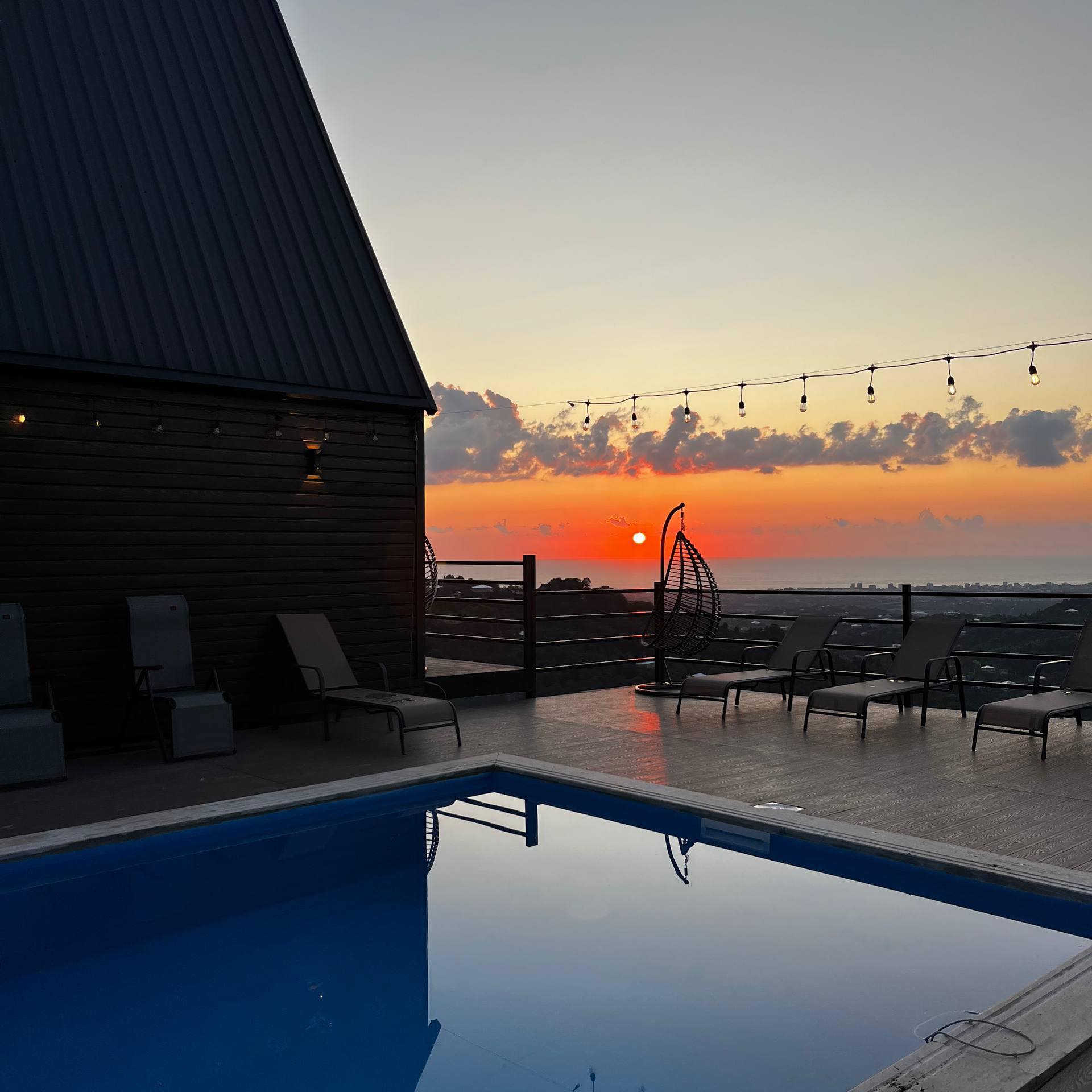 Aerial view of three A-frame cottages at Kvirike Hills with the Black Sea on the horizon